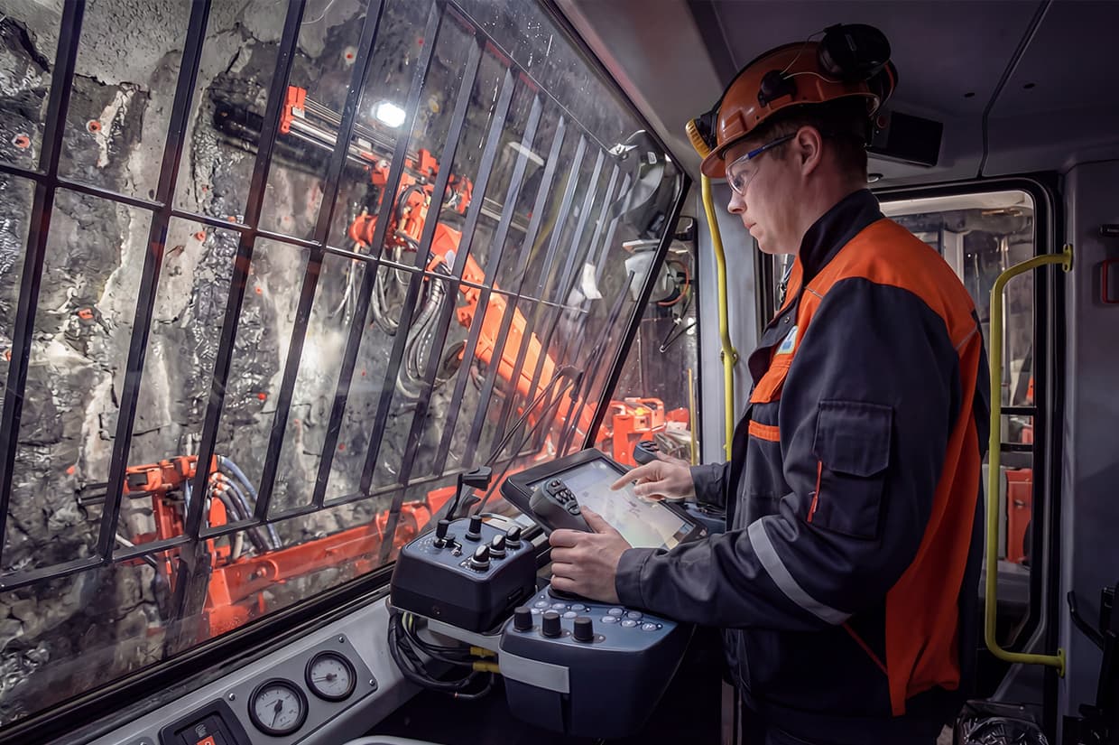 Industrial touchscreen panel operator using wireless remote control  to monitor heavy-duty mining equipment, demonstrating durability  and reliability of industrial-grade displays under extreme conditions
